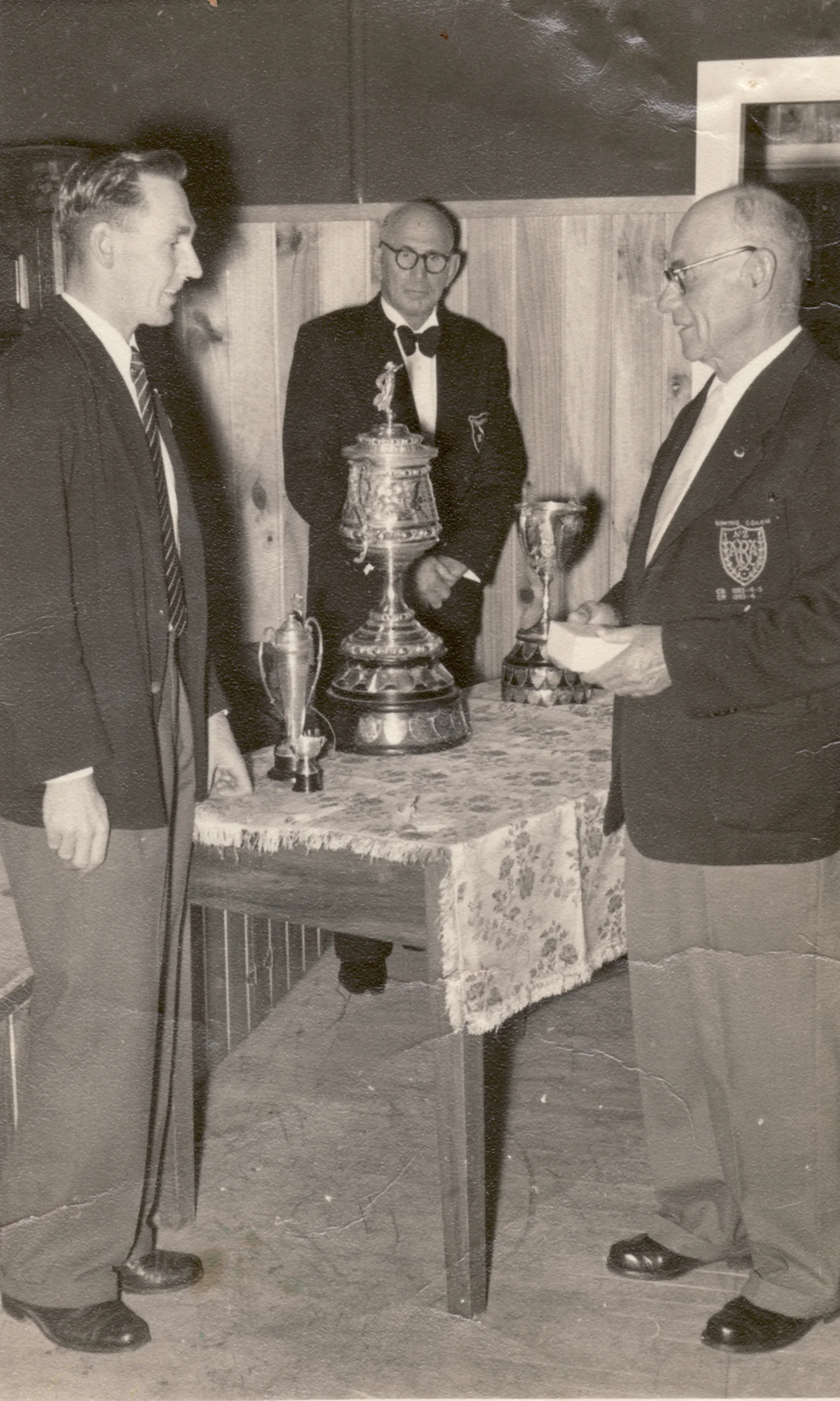 Picture taken at an end of season prize giving function shows Keith Bowering receiving an award from Cyril Molesworth with Harry Warren looking on in the background.