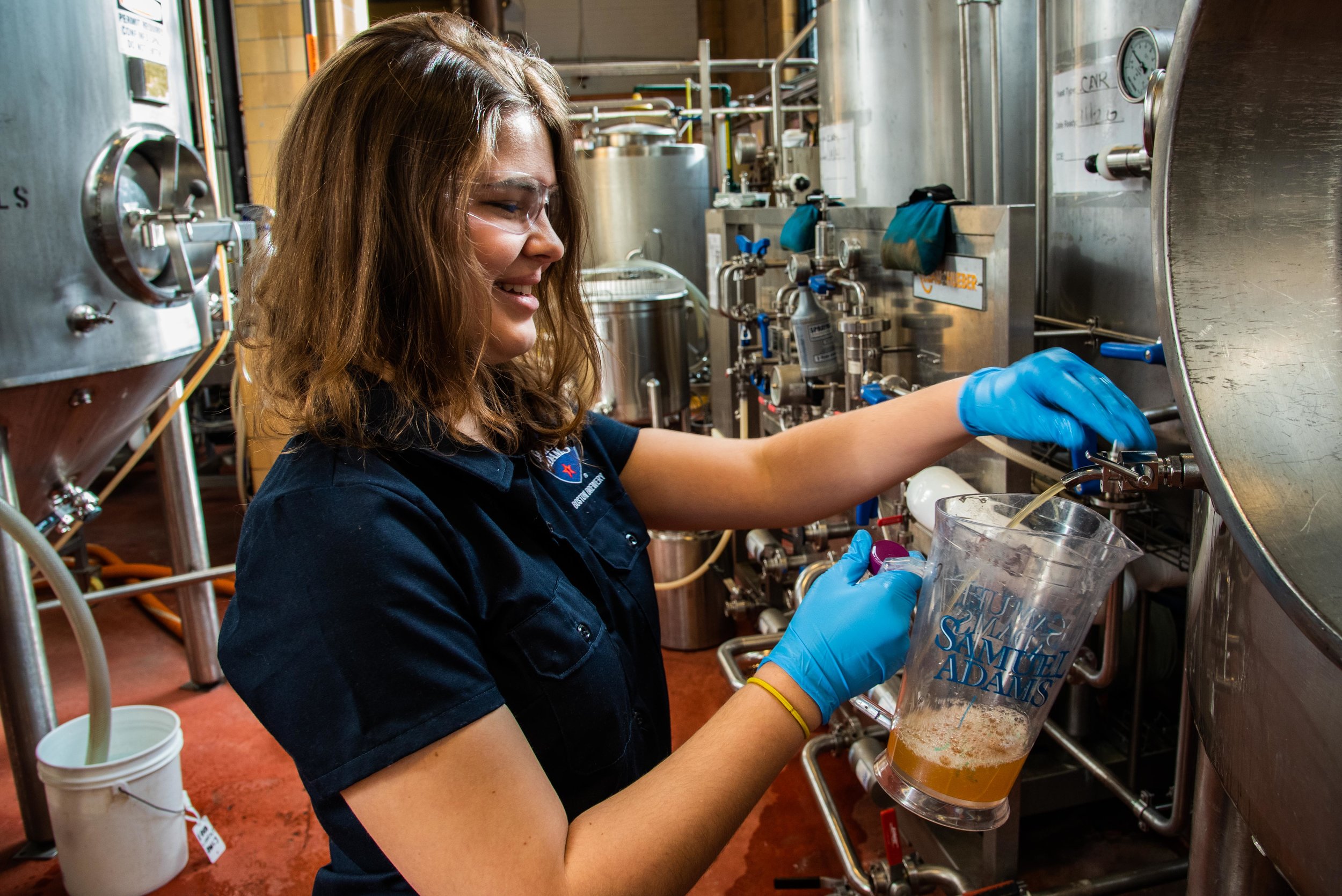 Elizabeth Curtis pulls a sample from a batch of beer mid-brew to test its consistency with other batches.