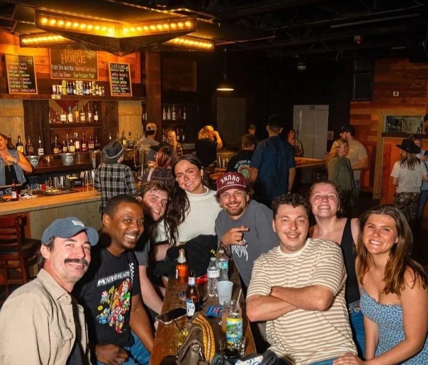 A group of friends gathered inside High Horse beneath the warm bar lights.