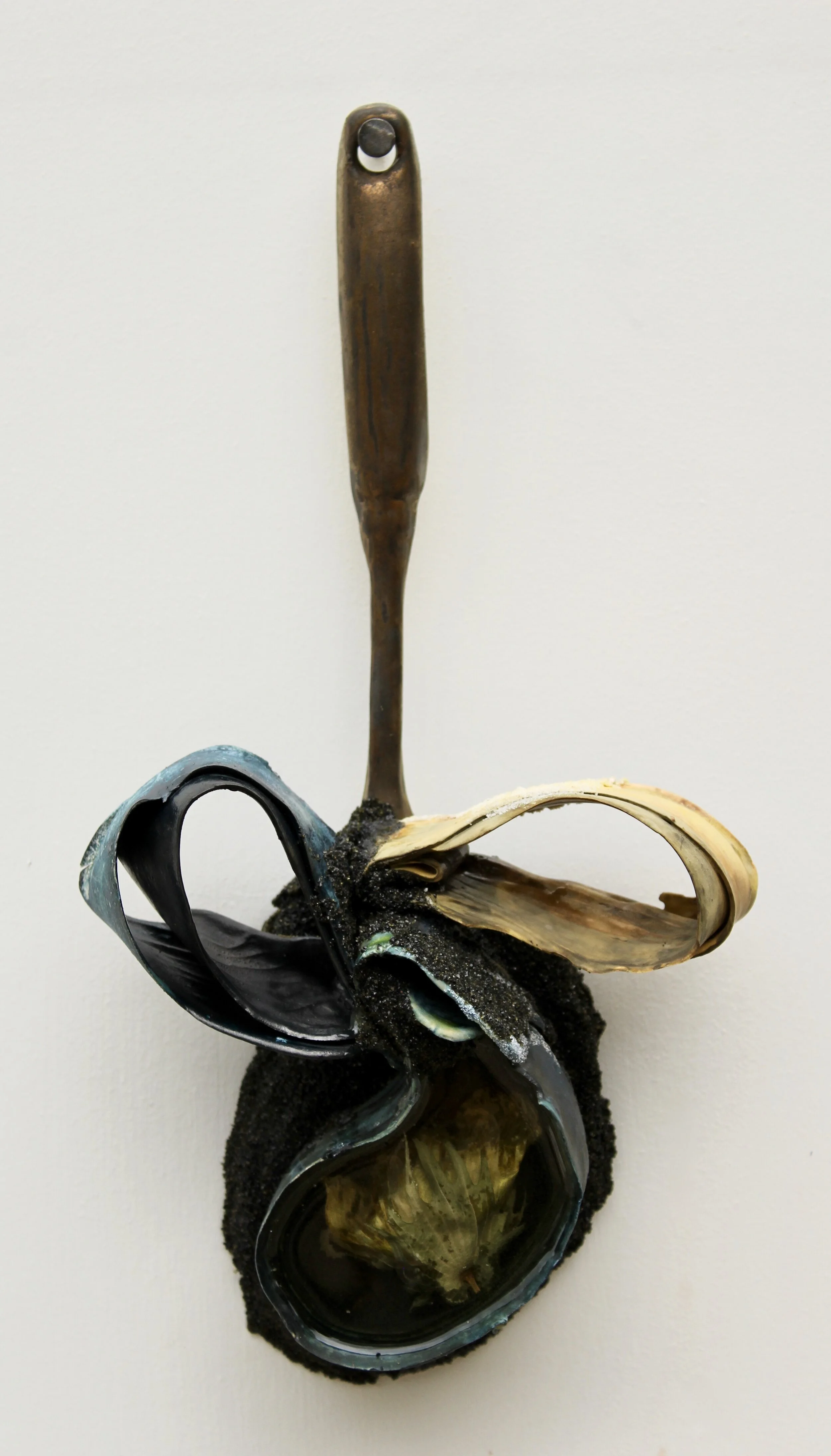 Memory Spoon: ‘plantation values, the tension and only available pride, as she waits for her cotton bushel weight to be revealed, then a victim of her success for another’s reward’; porcelain, paper clay, resin embed with cotton grown by artist, black sand, epoxy