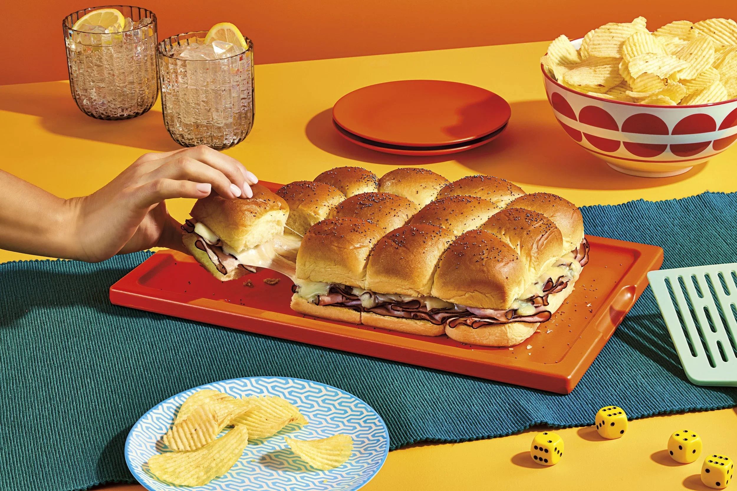 Hand pulling slider out of a kings Hawaiian ham and cheese bake