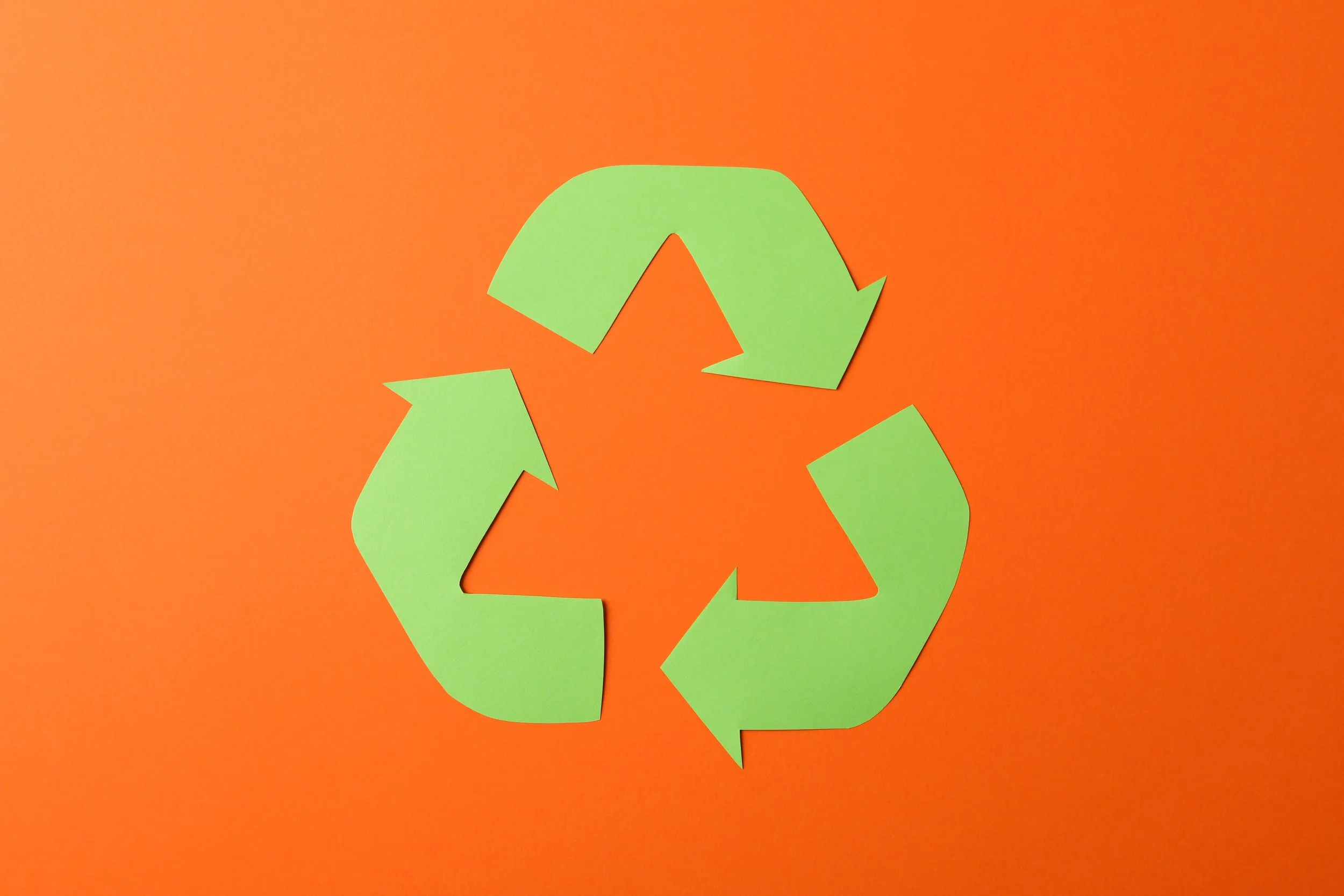 recycling-sign-on-orange-background-top-view-2023-11-27-04-56-17-utc.jpg
