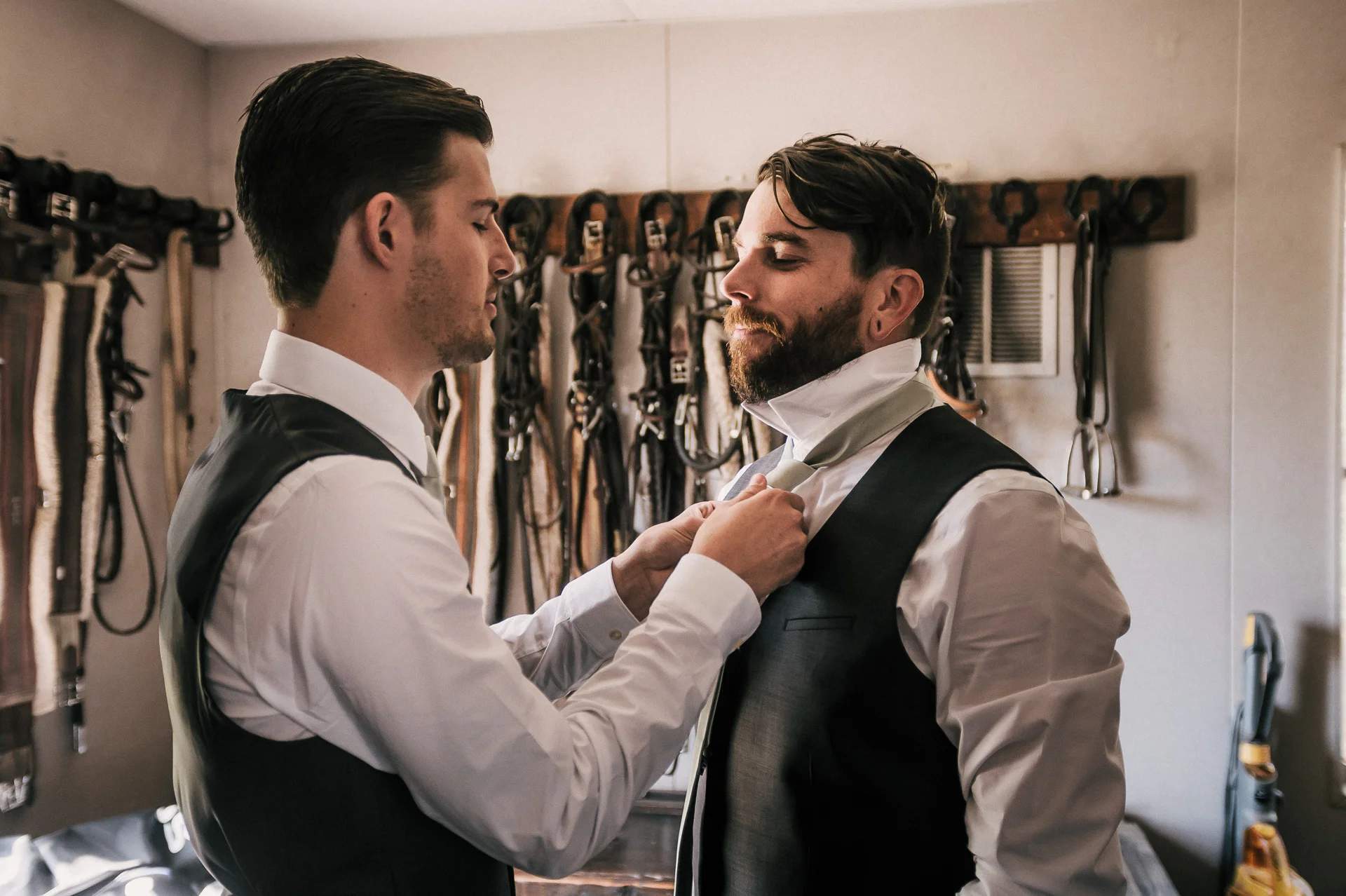 groom helps best man with tie