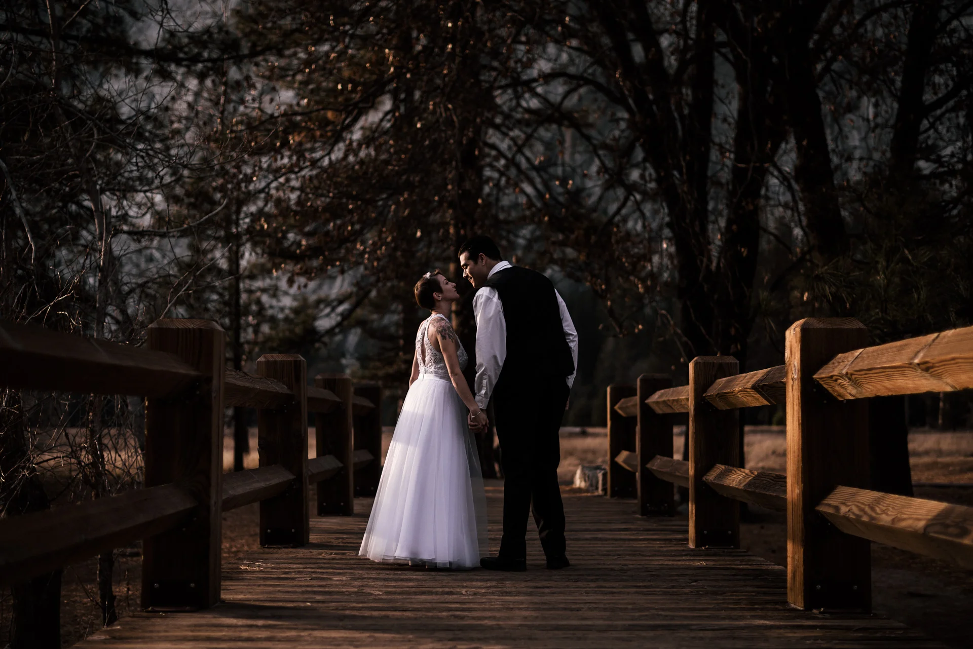 couple stops to kiss on the swinging bridge in yosemite