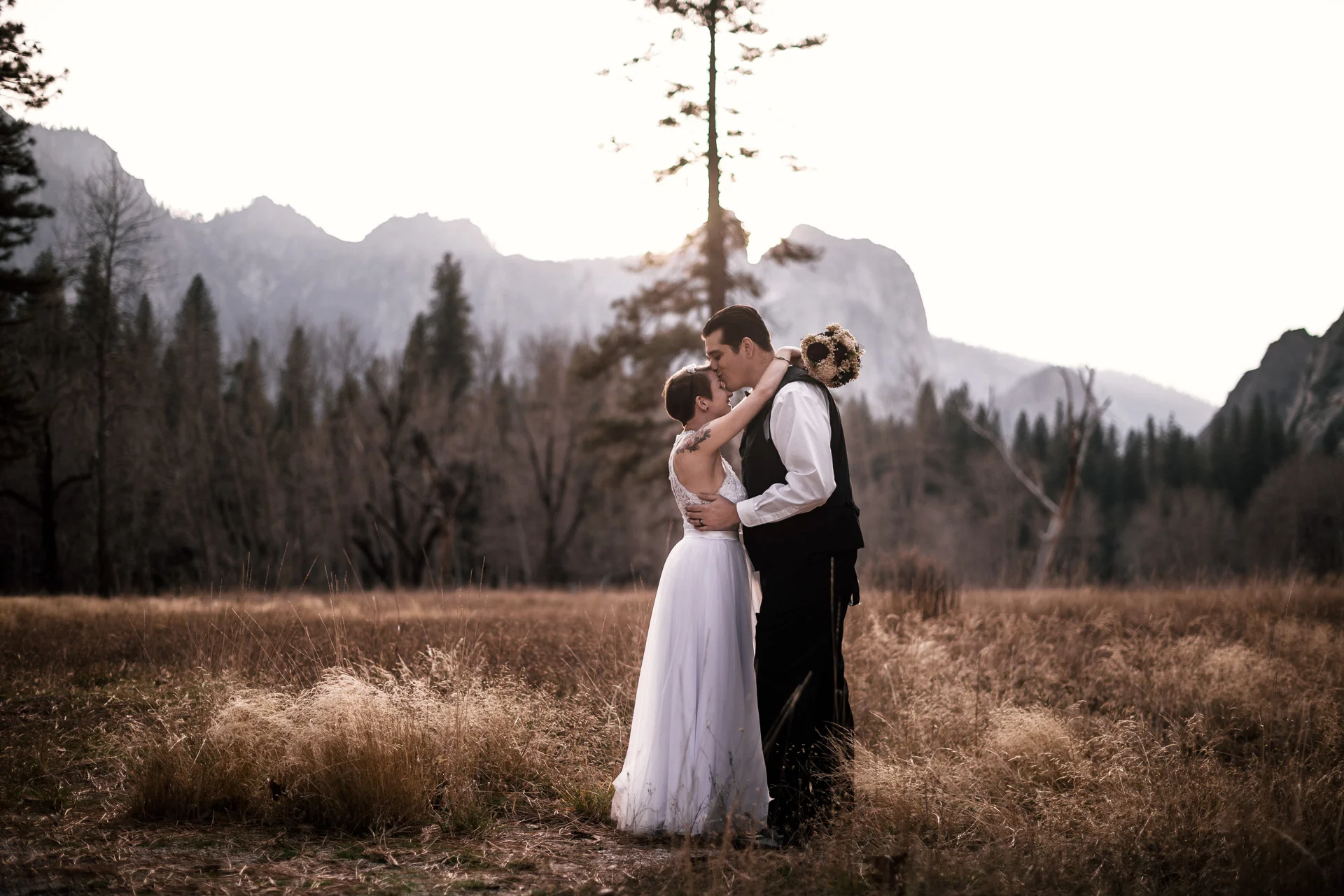 groom kisses brides forehead in a yosemite meadow at sunset