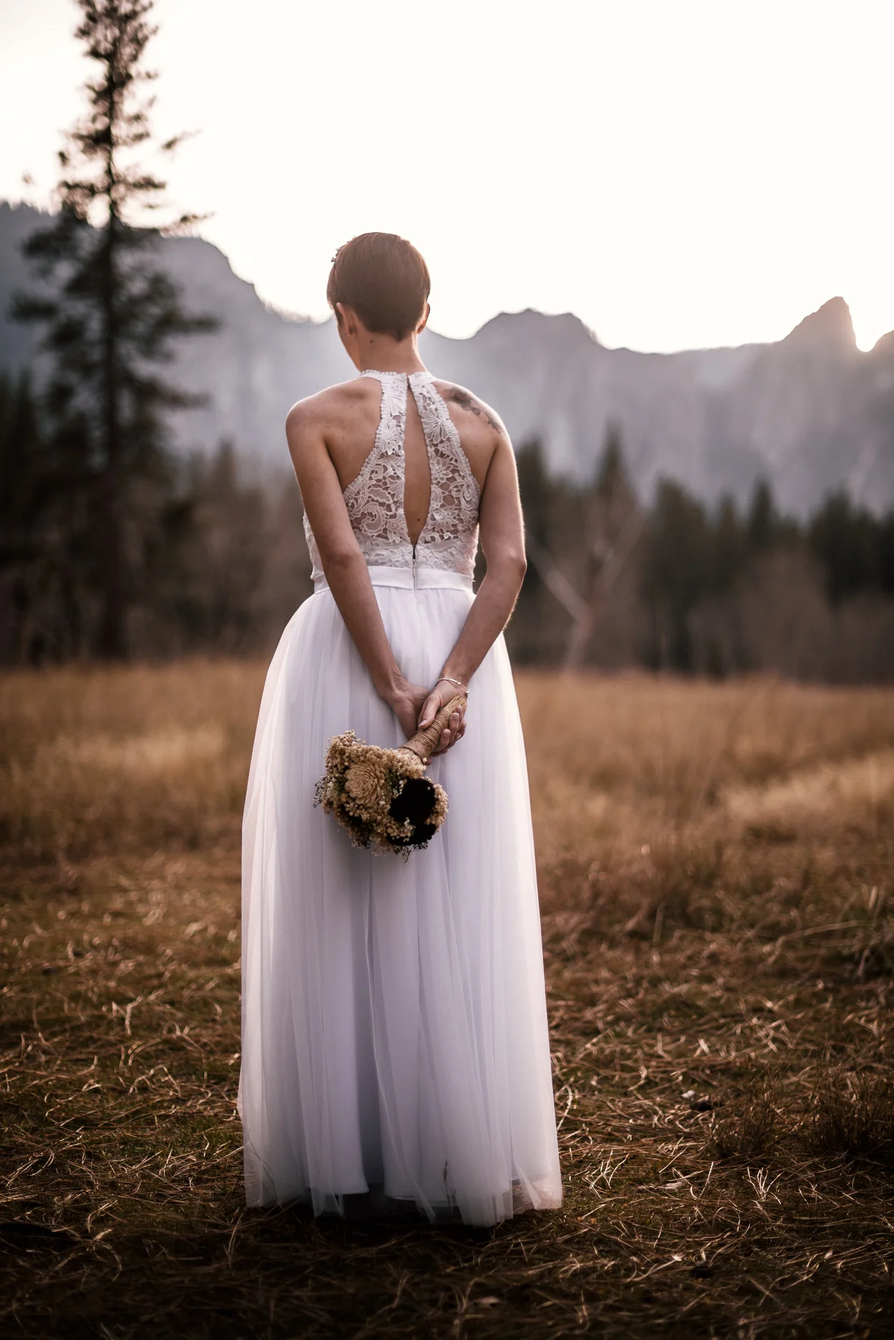Bride poses with bouquet showing the detials of her wedding dress in yosemite national park
