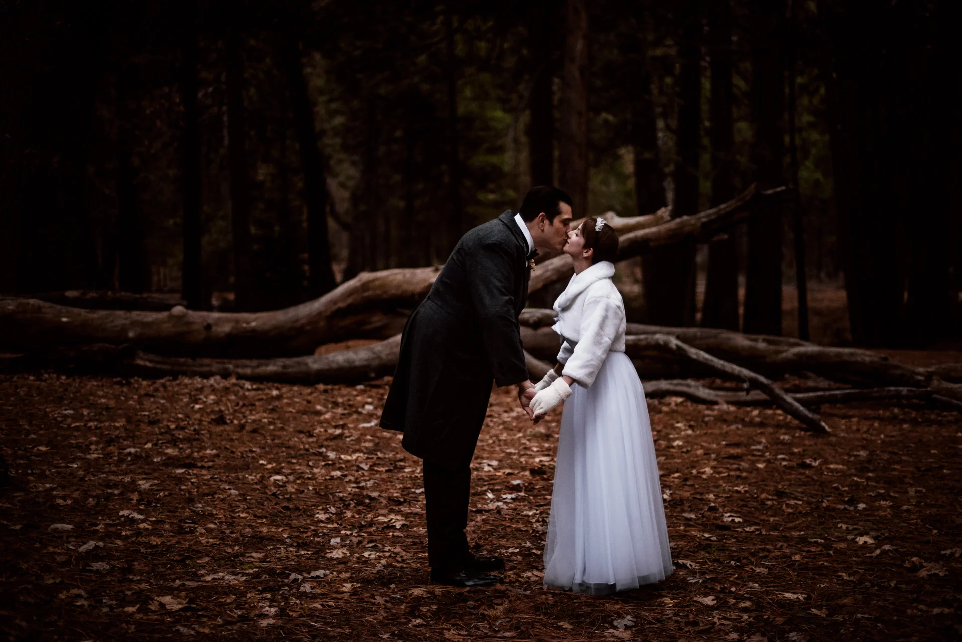 bride and groom kiss in winter for their Yosemite elopement at swinging bridge