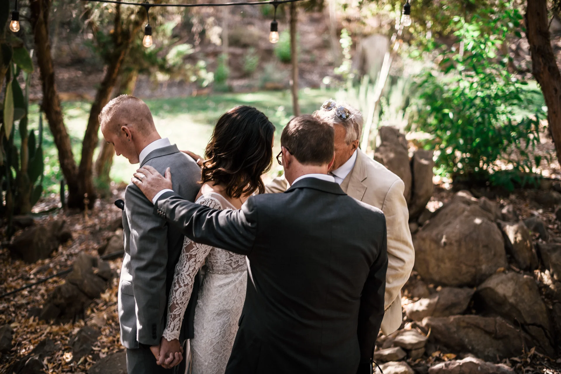 Bride and grooms fathers pray over them at rustic pymm ranch wedding venue in winchester california