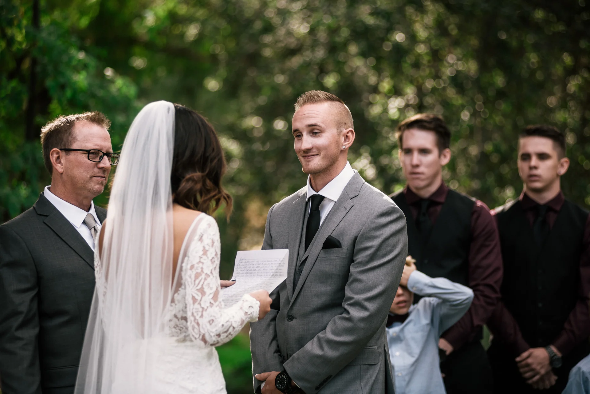 groom looks lovingly at bride reading letter at rustic pymm ranch wedding venue in winchester california
