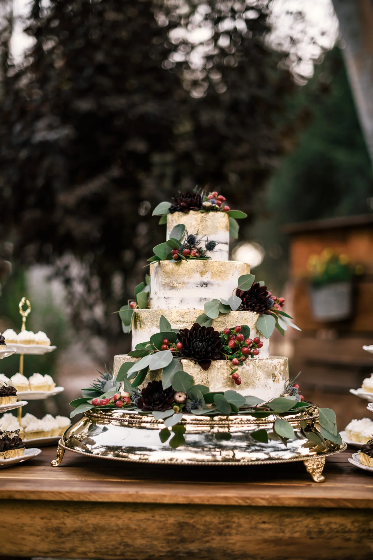 wedding cake with black flowers, gold leaf and eucalyptus details at rustic pymm ranch wedding venue in winchester california