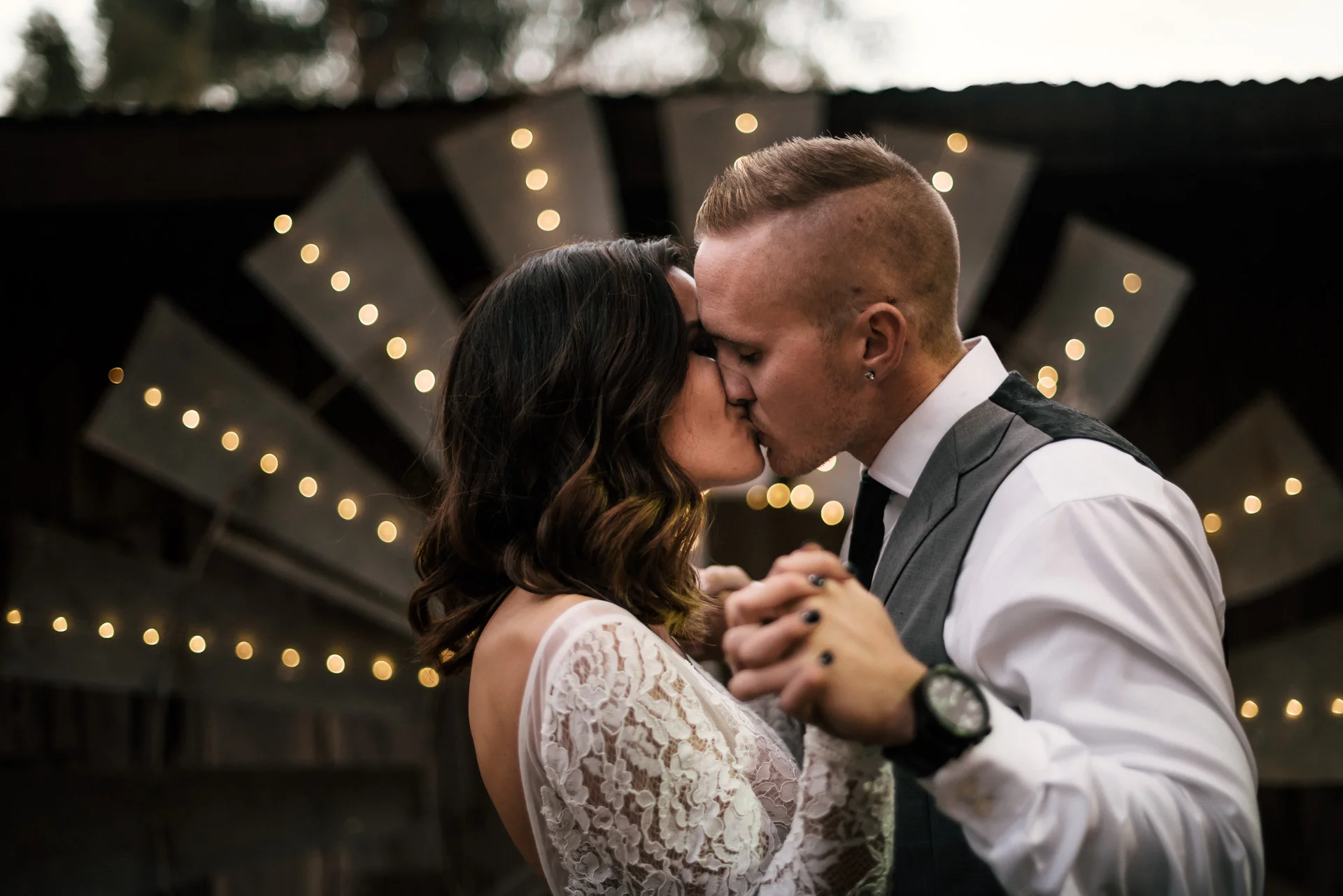kiss in front of a lighted windmill at rustic pymm ranch wedding venue in winchester california