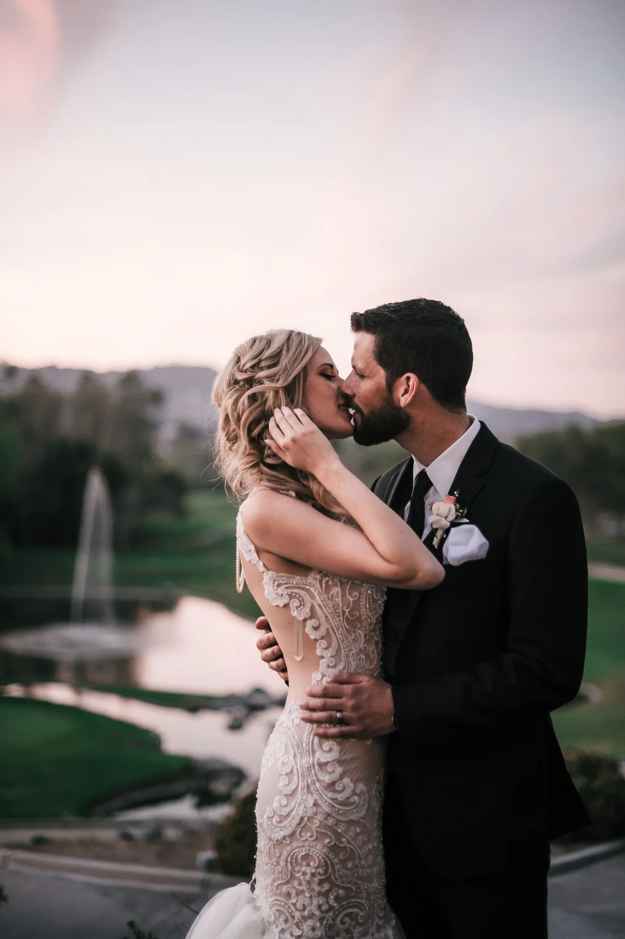groom romantically kisses bride at sunset at the Twin Oaks Golf Course in San Marcos, San Diegos premier wedding venue