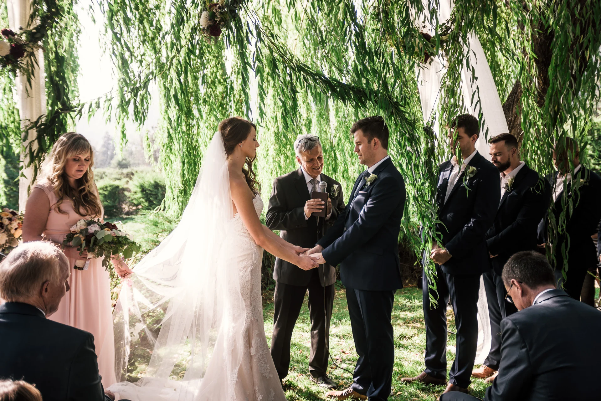 bride and groom hold hands at wedding ceremony at the secret garden located at the Historic Parish ranch in Oak Glen California