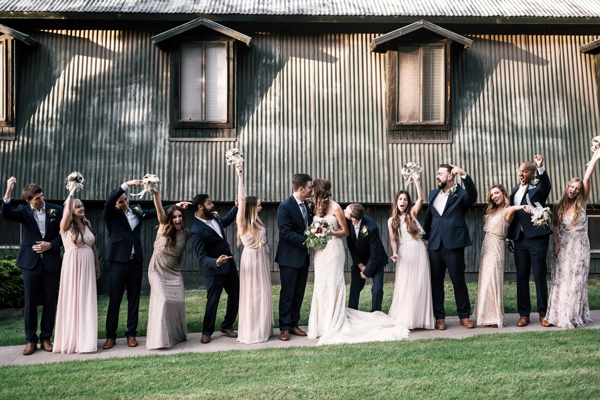 bridal party cheers as the bride and groom kiss at the secret garden located at the Historic Parish ranch in Oak Glen California