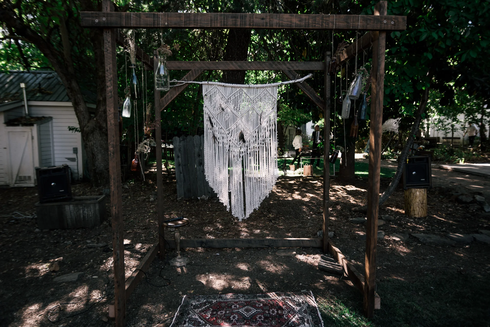 handmade wooden arbor decorated with colored glass bottles and macrame shot by wedding photographer at the charming St. George Hotel in Volcano California