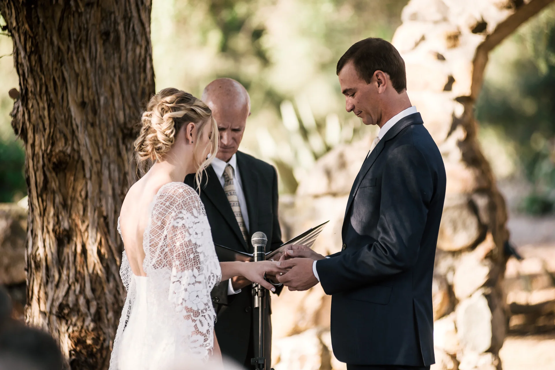 groom puts ring on brides finger captured by photographer during romantic wedding at the historic Leo Carrillo Ranch in Carlsbad California
