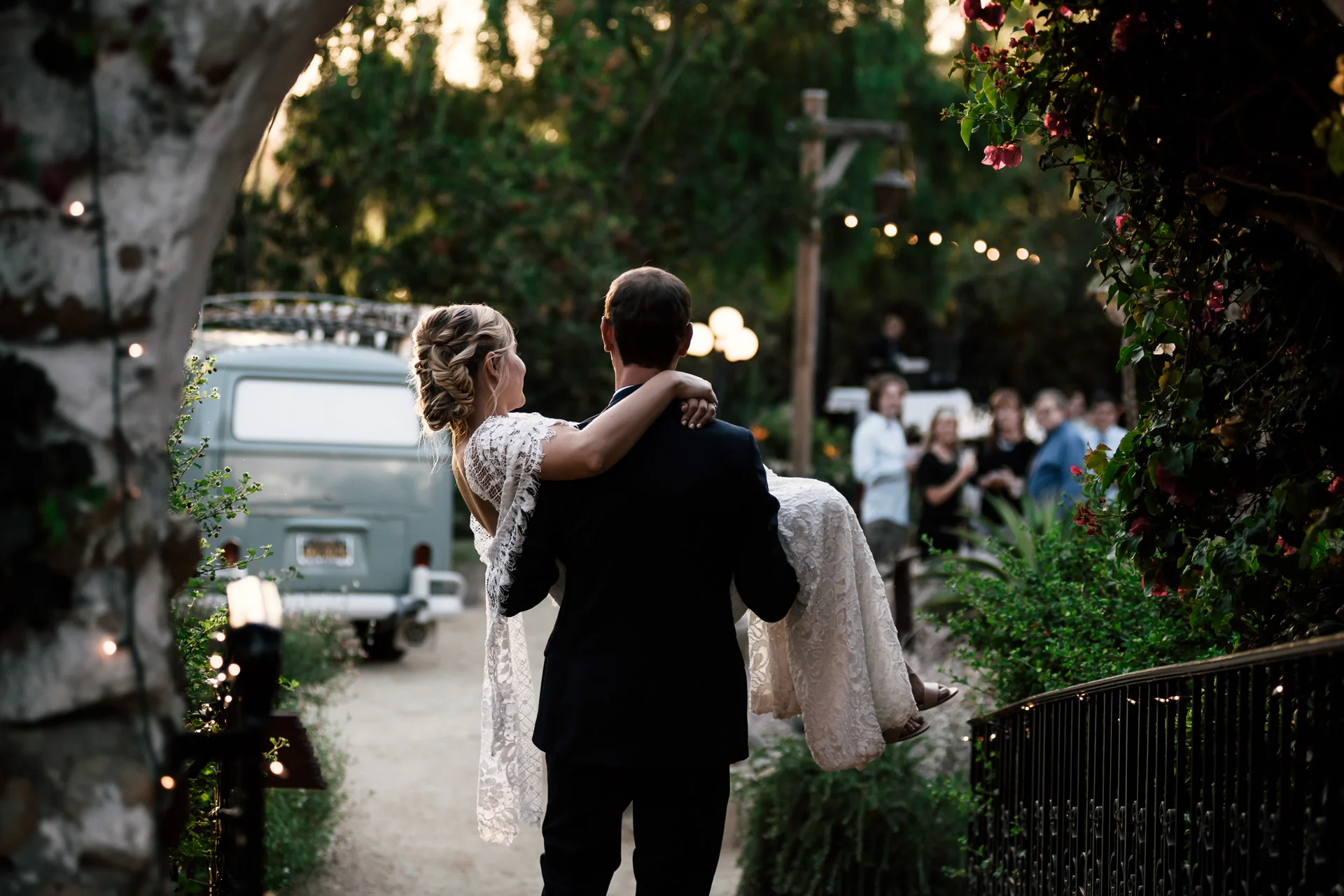 groom carries his bride to the reception captured by photographer during romantic wedding at the historic Leo Carrillo Ranch in Carlsbad California