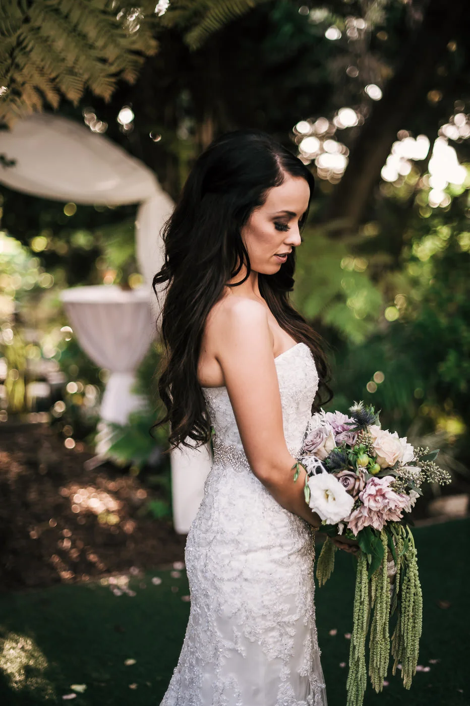 Beautiful bride poses with her elegant bouquet after a romantic ceremony at the San Diego Botanical Garden.