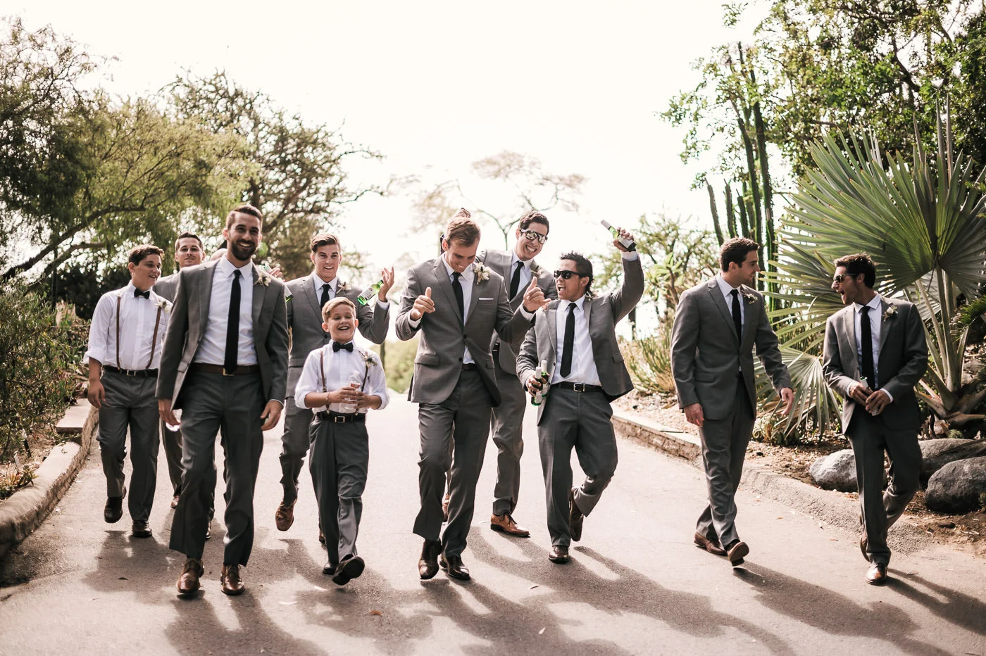 Groom and his groomsmen head to the wedding reception in the San Diego Botanical Garden to celebrate with drinks in hand.