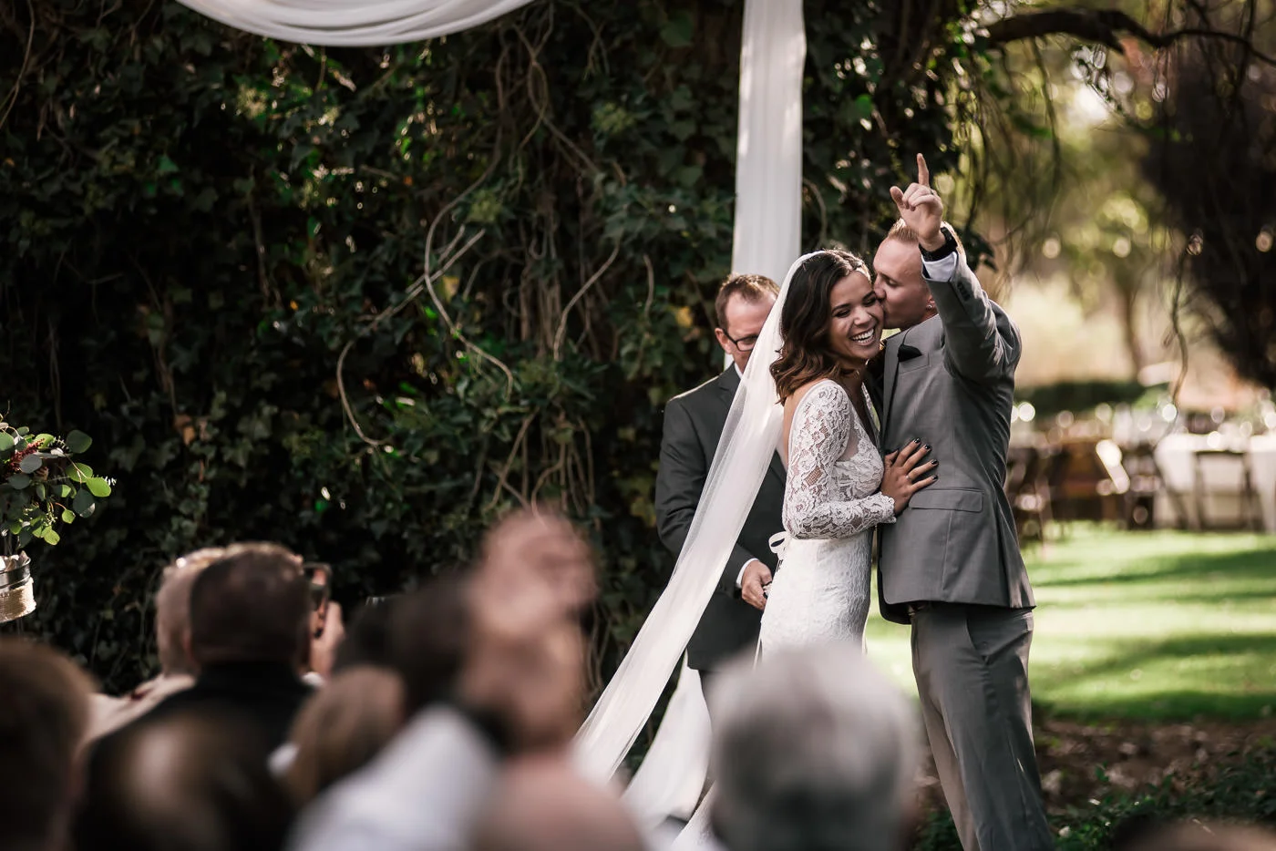 Groom celebrates and kisses brides cheek at rustic Pymm Ranch venue in Winchester California.