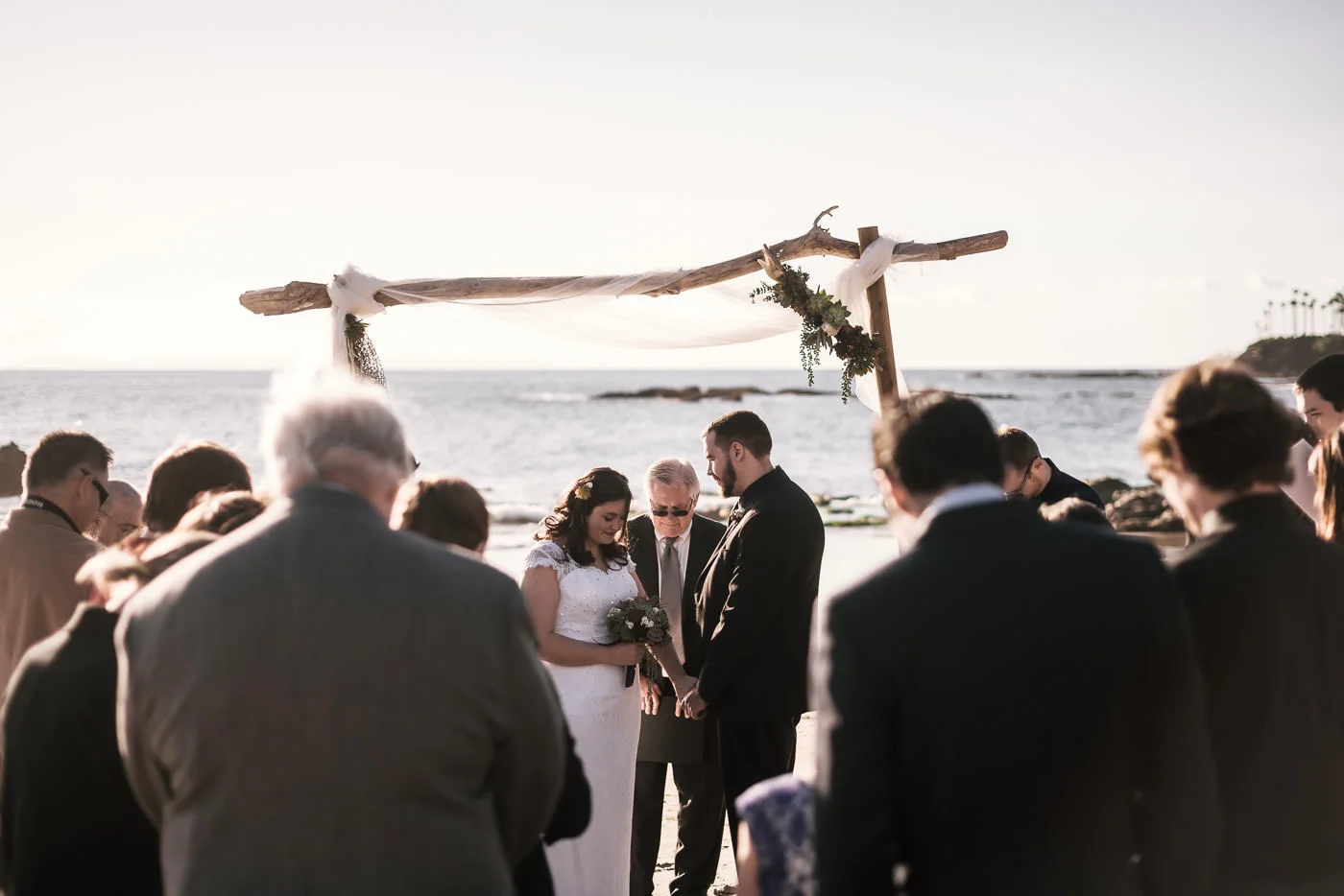 Couple has an intimate marriage ceremony on the shoreline beneath a driftwood altar in Laguna Beach.