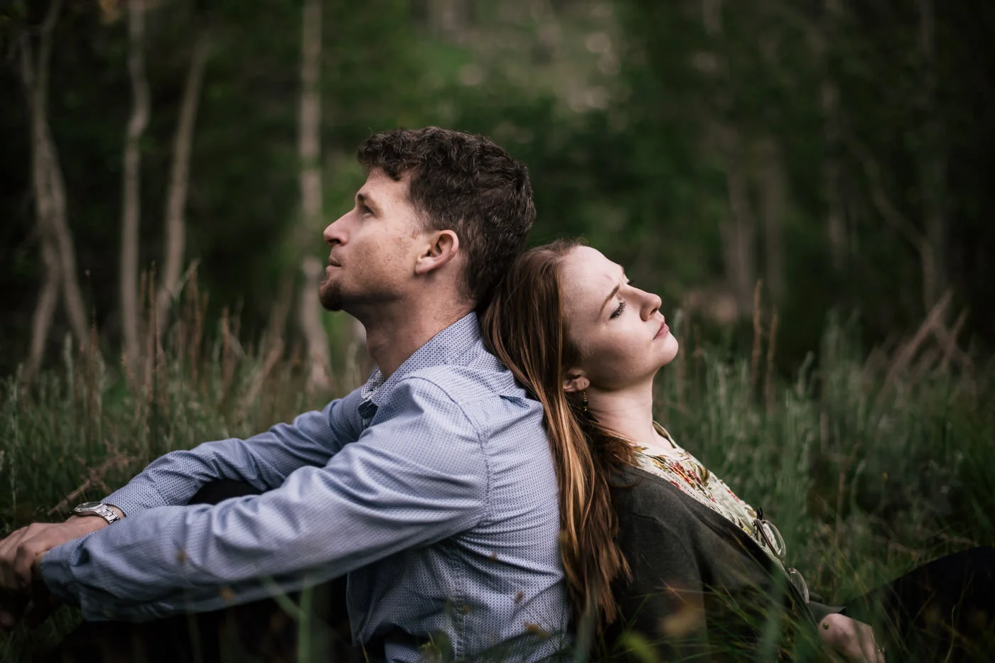 Couple sits in a meadow back to back and enjoys a quiet moment alone during their engagement session in Sequoia national park.