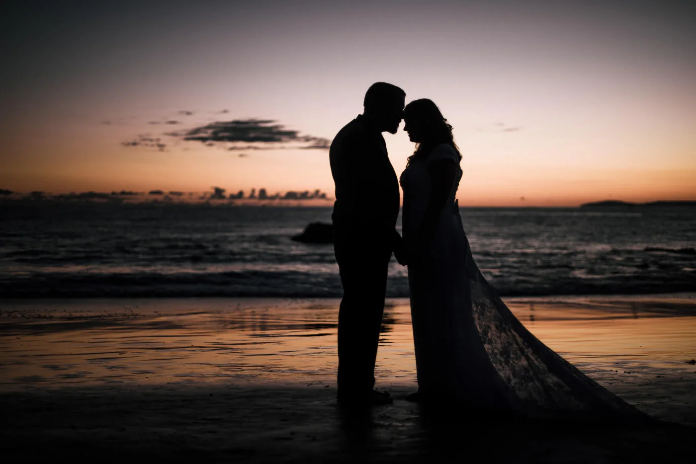 couple in love silhouetted against the sunset after a romantic wedding in Laguna Beach.