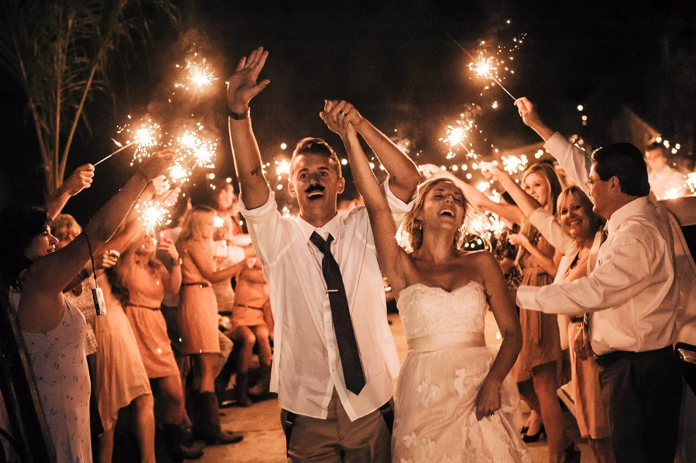 Couple cheers as they make their grand exit lined by family and friends with sparklers at their vintage themed Temecula Wedding.