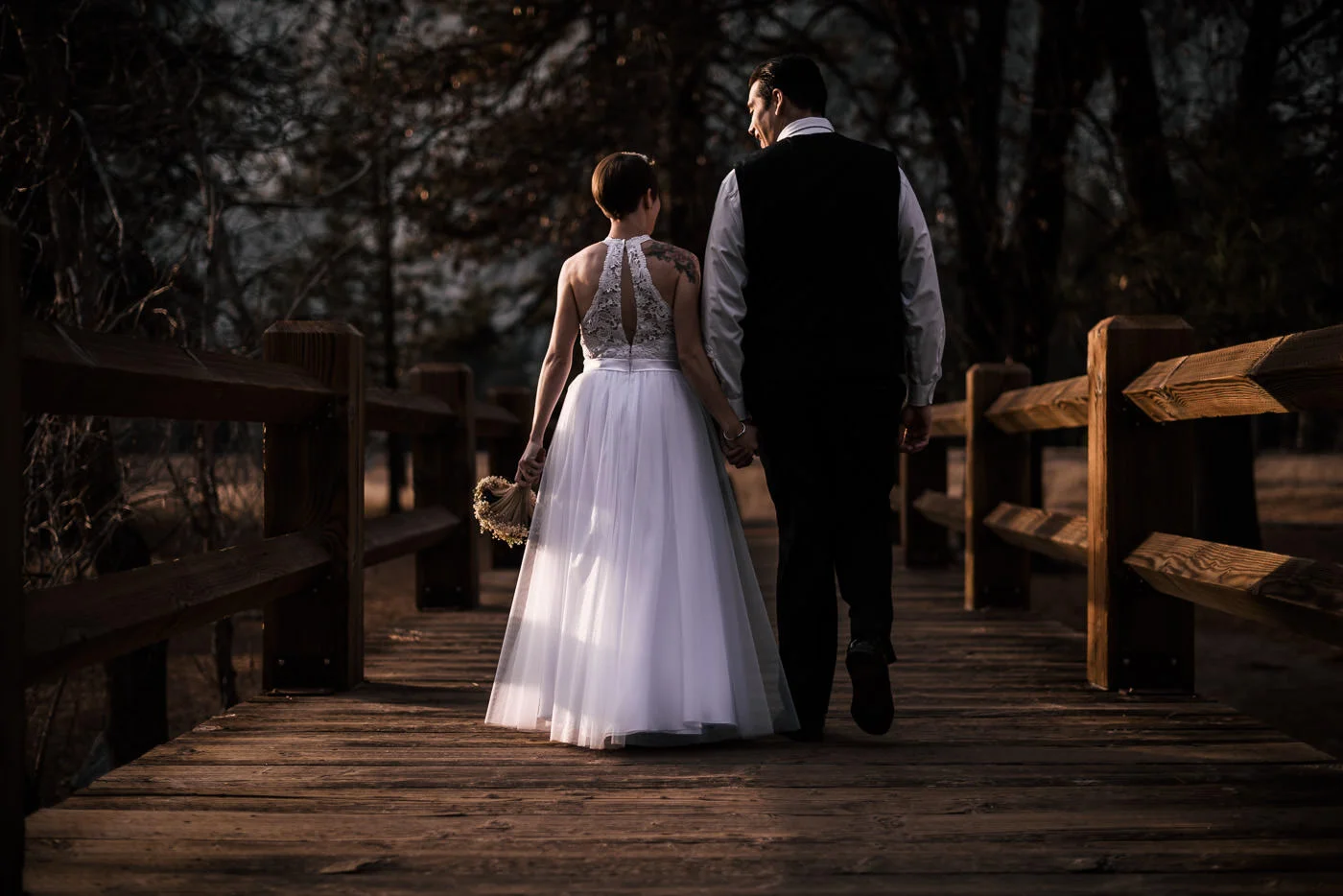 bride and groom walk down swinging bridge