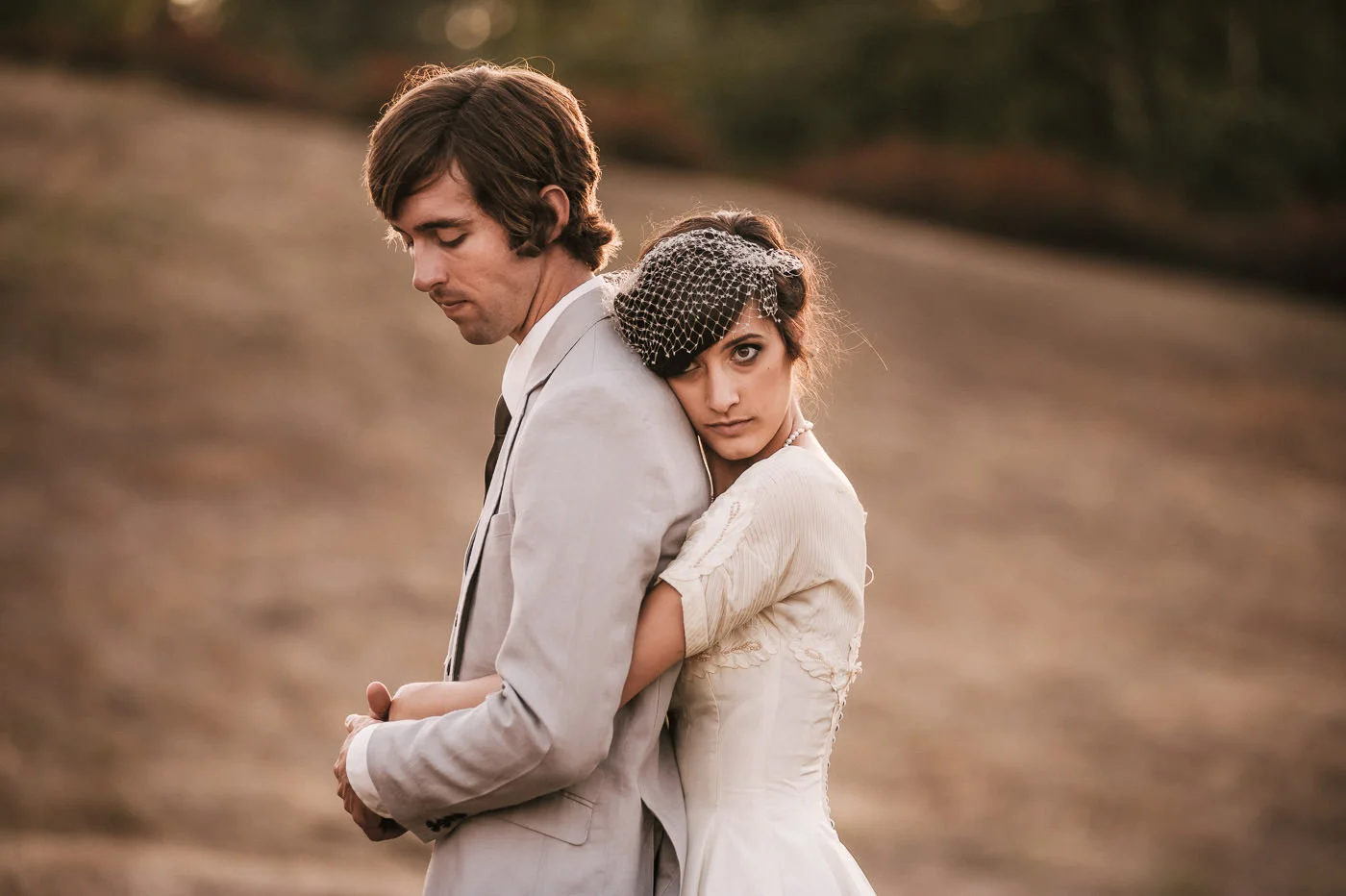 Bride wraps her arms around her man and rests her head against his back after their temecula wine coutnry wedding