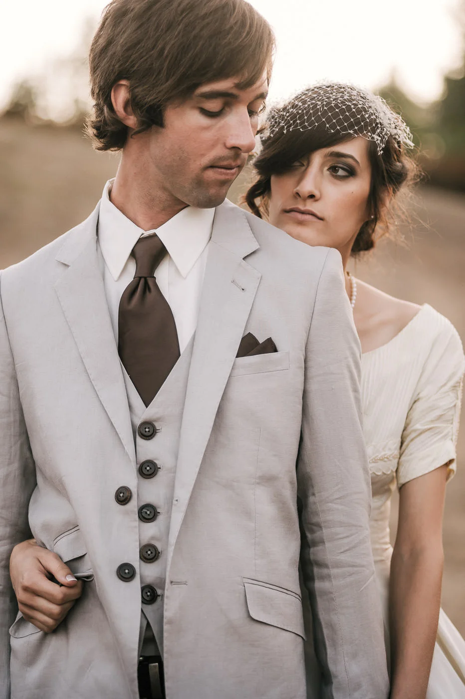Bride puts an arm around the groom and plays with his coat pockets