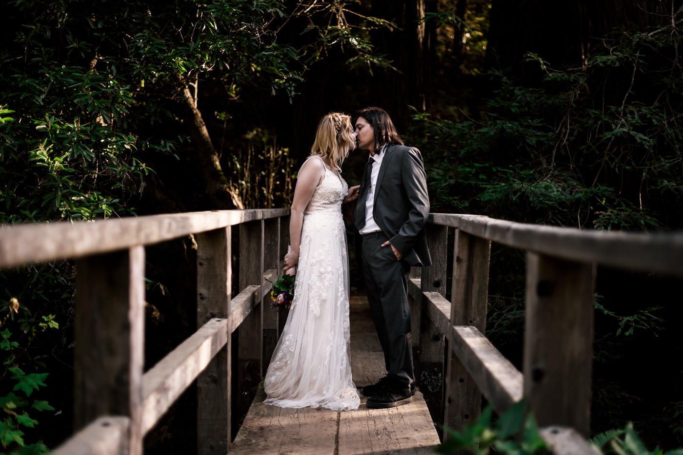 Romantic Kiss on an old wooden bridge spanning a creek after an elopement in Big Sur Salifornia