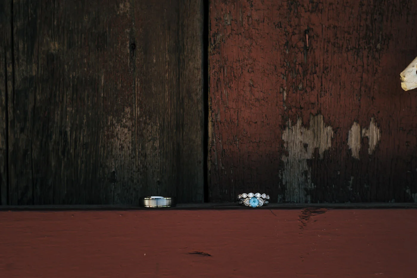 beautiful wedding ring with blue diamond sits against a rustic red wall