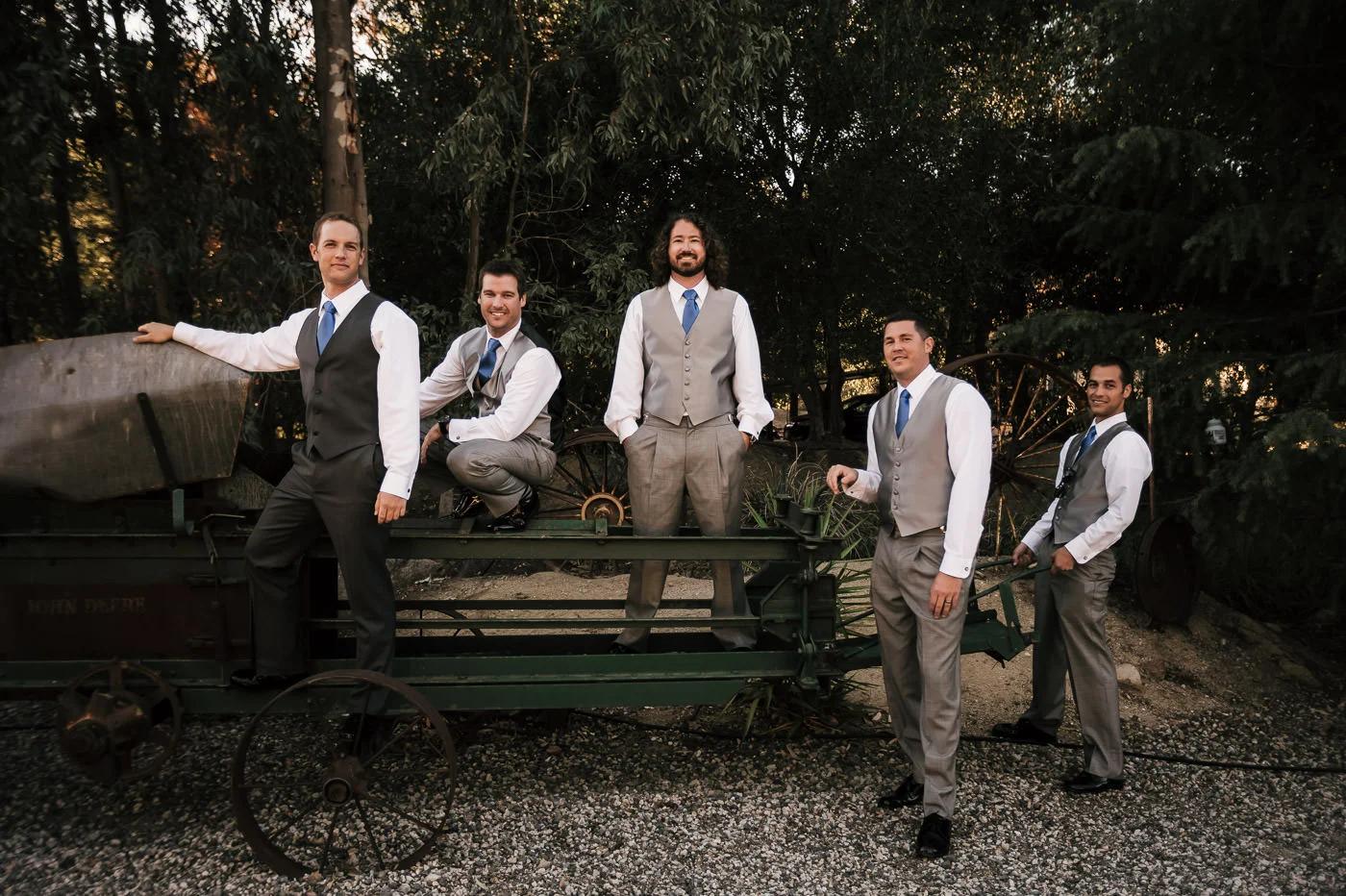 groom and his groomsmen poses on some old farm equipment