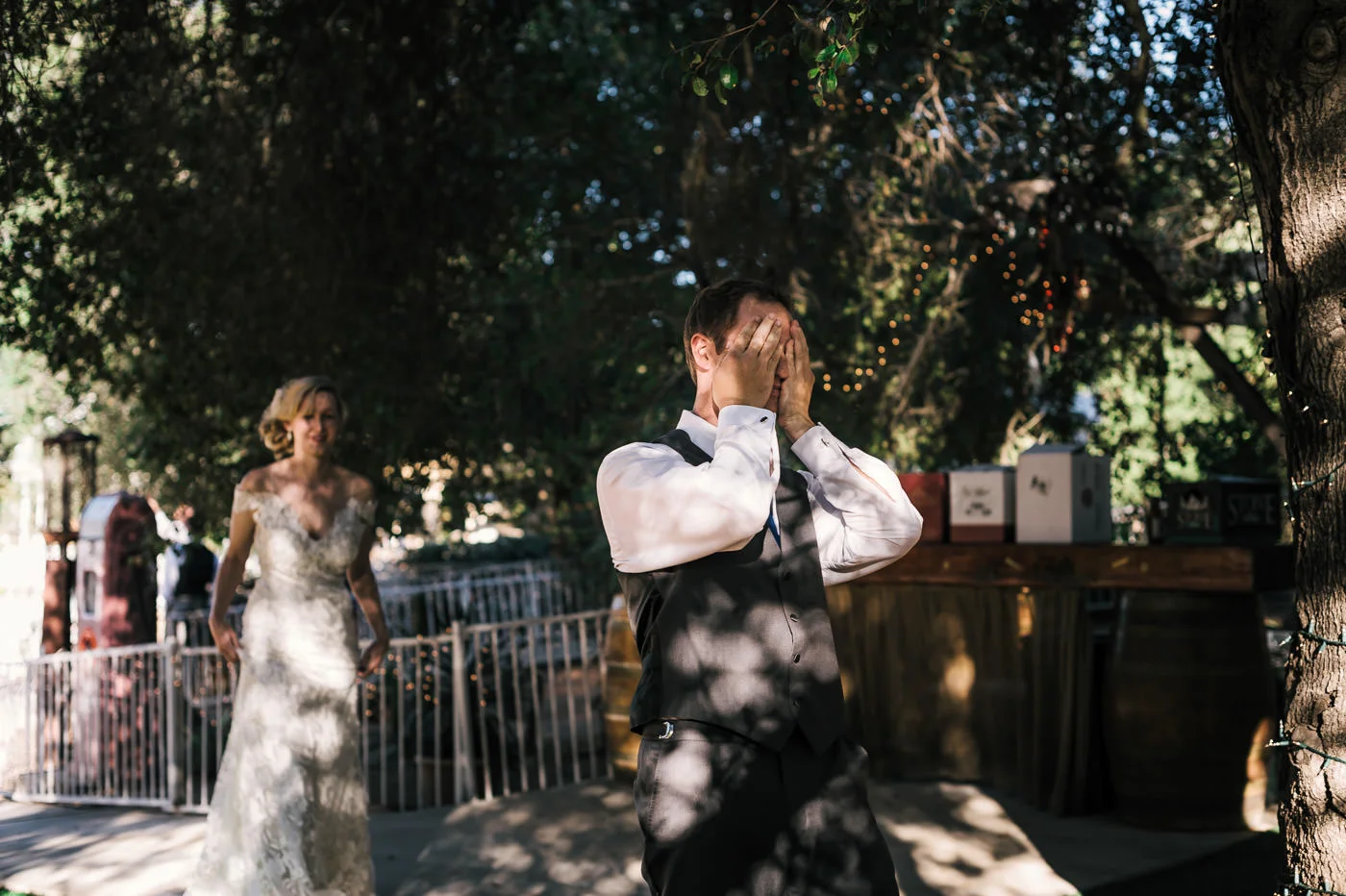 groom covers his eyes as the bride approaches for the first look at their country styled wedding.