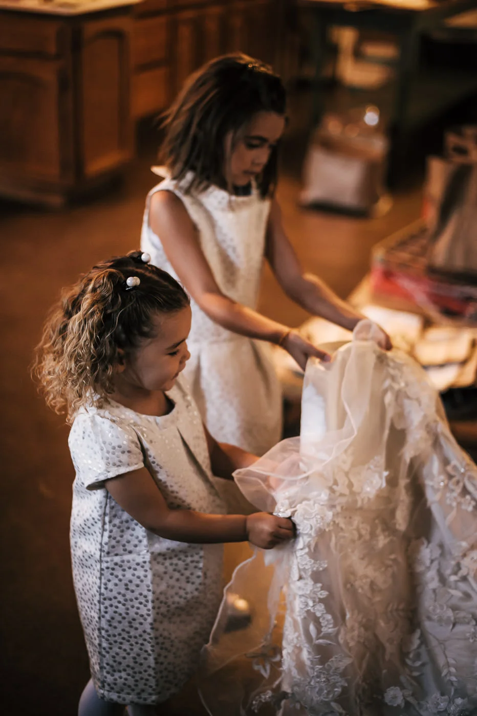 flower girls hold up the brides train while she get's ready for the wedding