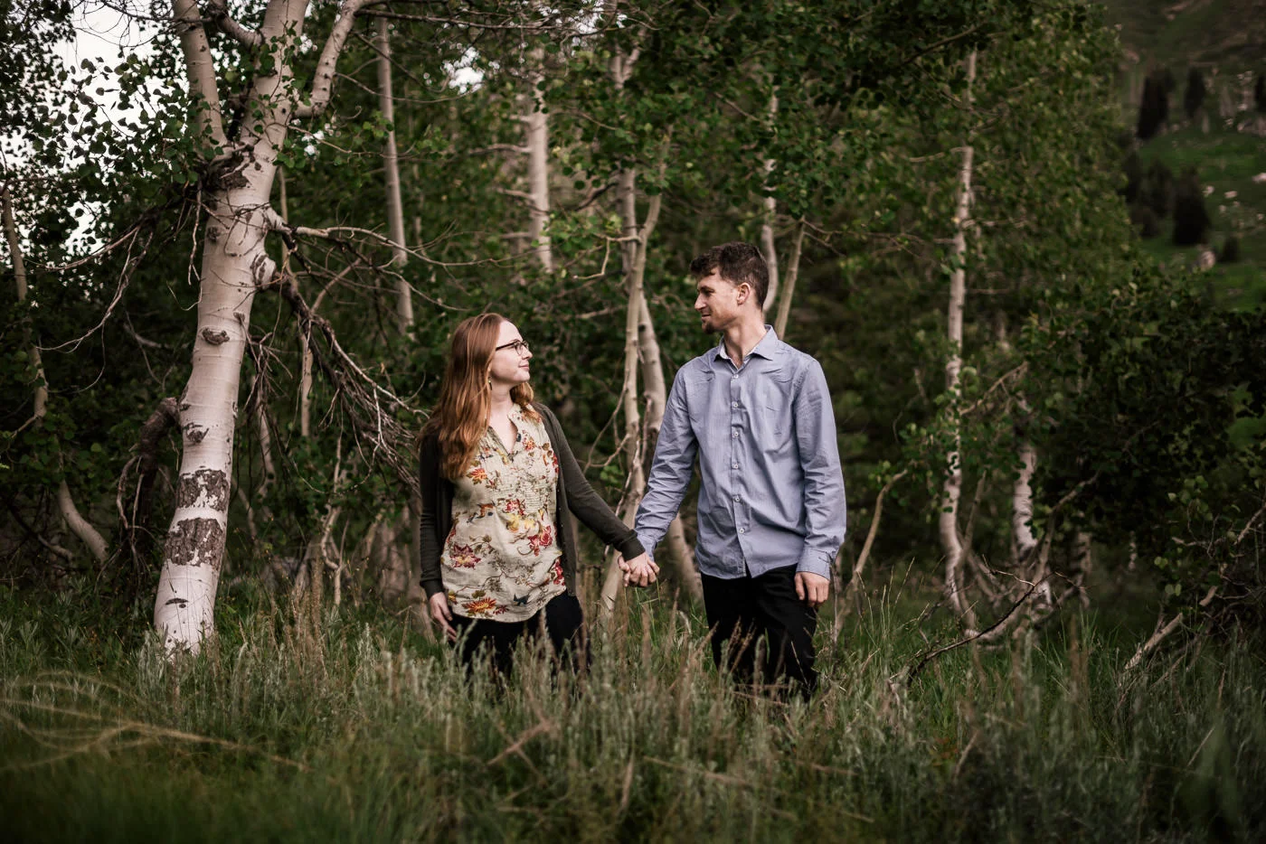 hand in hand two lovers walk through a quiet meadow surronded by birch trees for a romantic engagement session in Sequoia National Park
