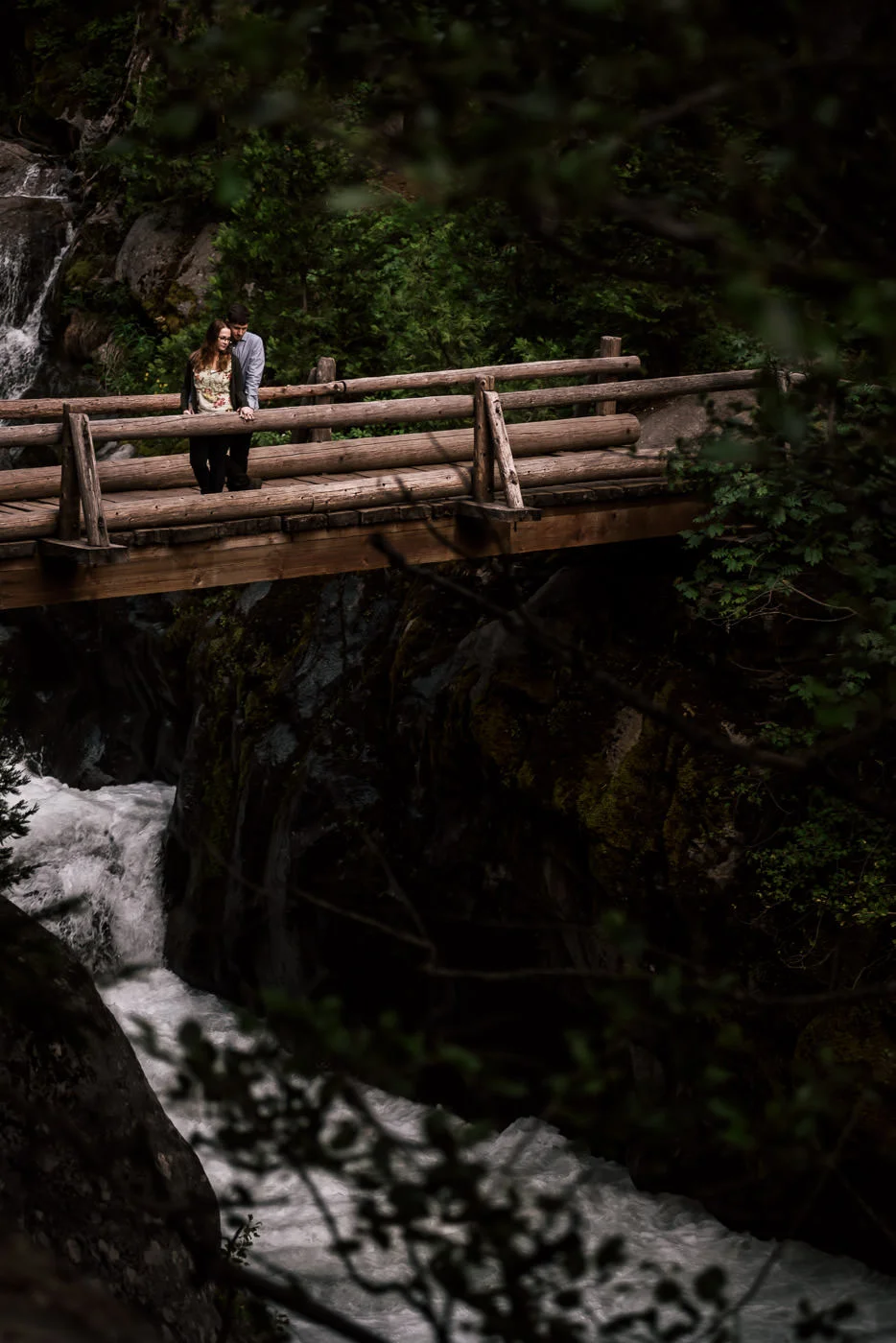 An old wooden bridge spanning the churning water of the river below makes the perfect setting for a romantic engagement photo in Sequoia National Park