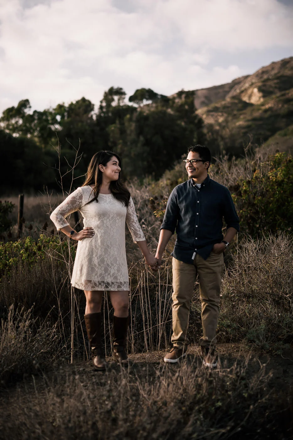 Couple stands side by side in the light of the setting sun on the cliffs of malibu for their engagement.
