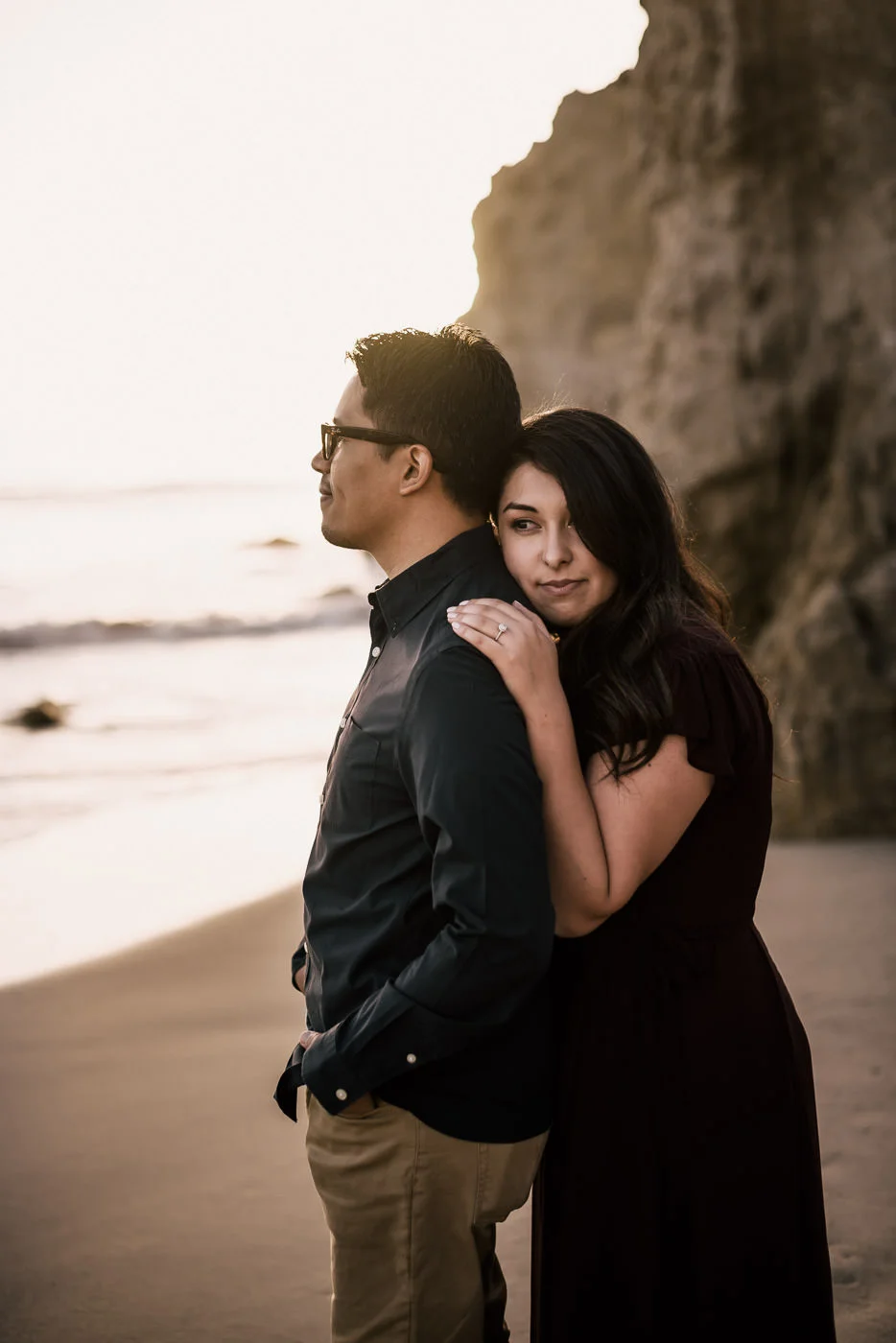loving bride to be rests her head on her man and enjoys a romantic moment on the beach