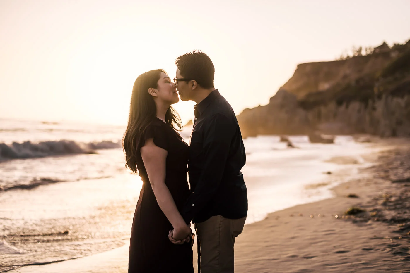 Heartfelt kiss on the beach in Malibu awash in the golden light of sunset.