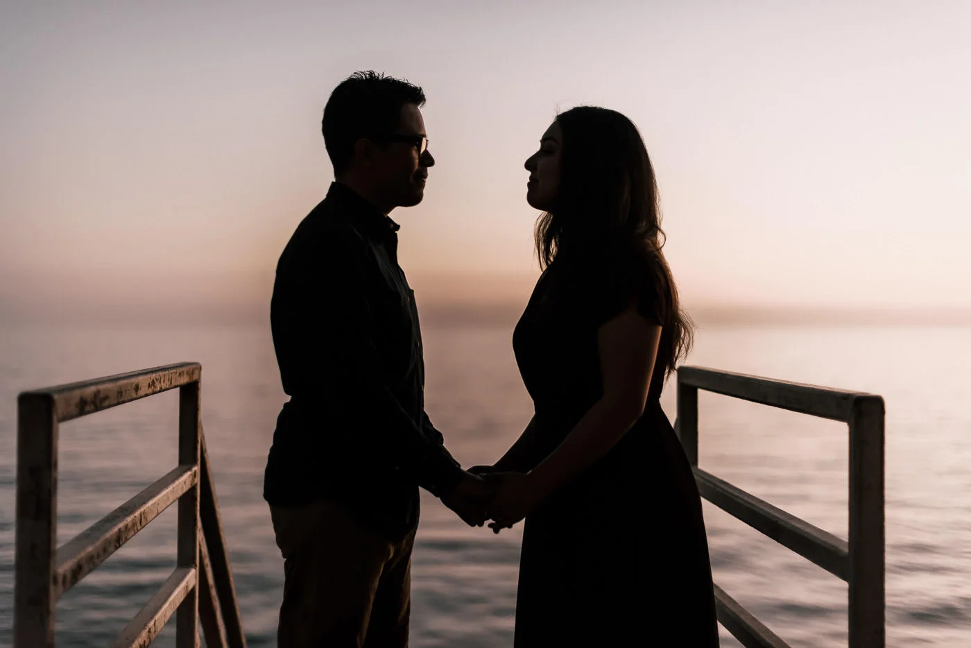 Sillhouetted by the bright light of the setting sun this couple grab each others hands and stared lovingly into each others eyes during their engagment session.