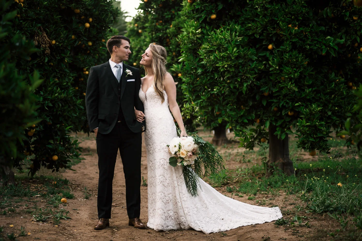 Gorgeous couple poses for their wedding photographer and create a romantic portrait in this stunning orange orchard in Temecula California.