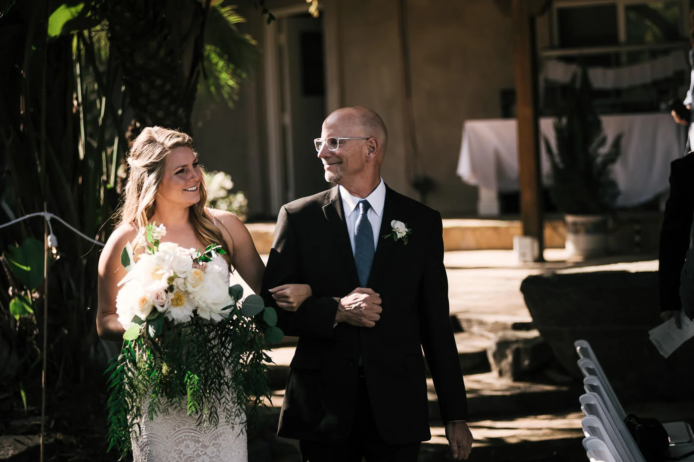 Father walks the bride down the aisle with smiles all around. A touching moment captured by their Temecula wedding Photographer