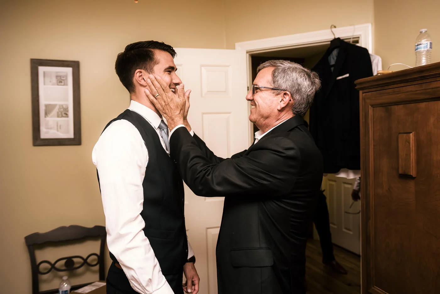 father lovingly grabs his sons face to congratulate him on his wedding in Temecula California