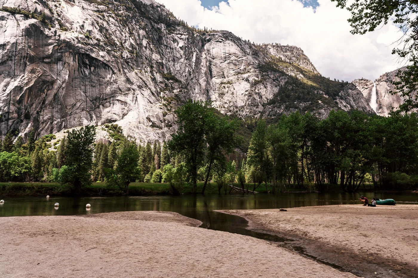 The sandy shores of Sentinel beach with the looming granite peaks of the Yosemite Valley in the background.