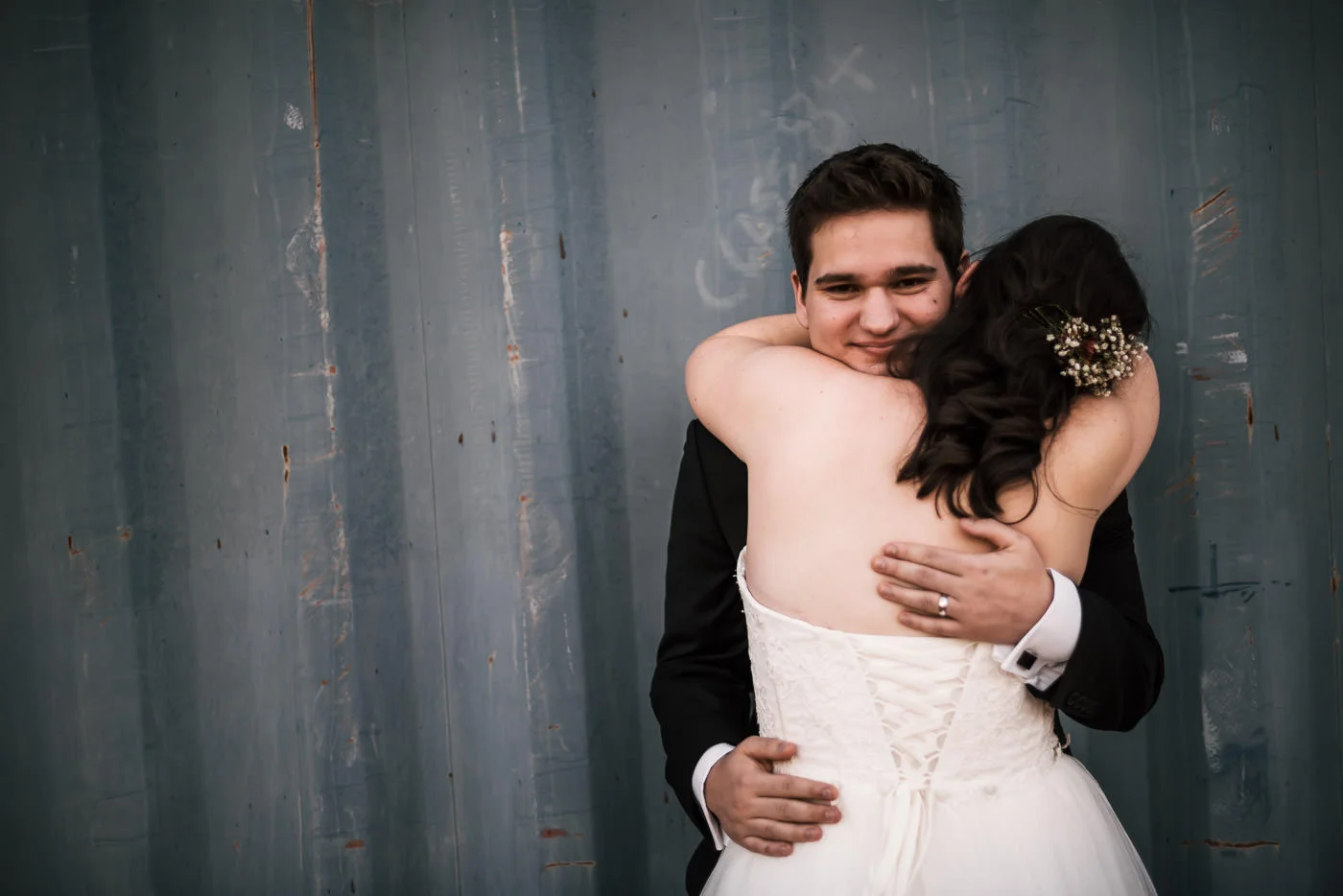 Happy groom holds his bride close with a big smile.