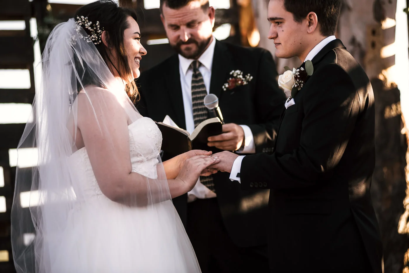 Bride laughs as she places the wedding band on her husbands finger.