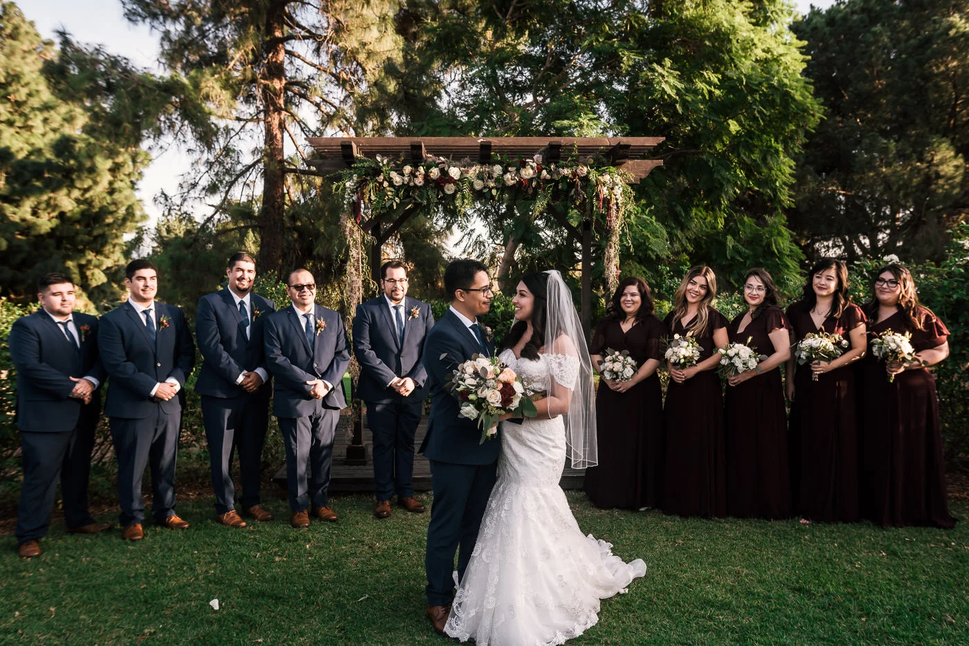 Bride and groom hold each other as they pose for photos with their wedding party.