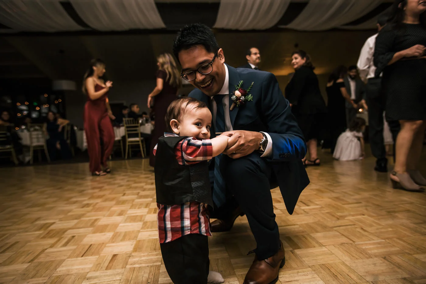 Groom dances with baby at wedding reception.